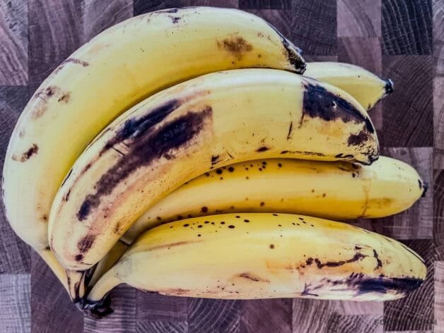 A bunch of ripe bananas with dark spots on their yellow skins, ideal for making banana bread.