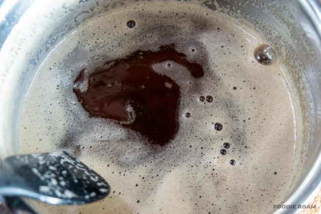 A saucepan with golden brown butter and foam on the surface.