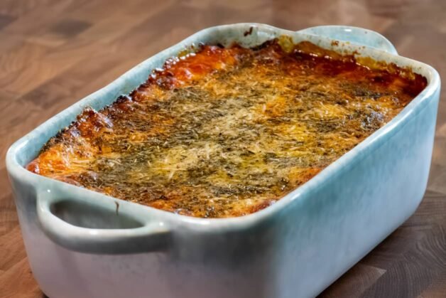 A golden, bubbling lasagna resting in a baking dish after being freshly baked.