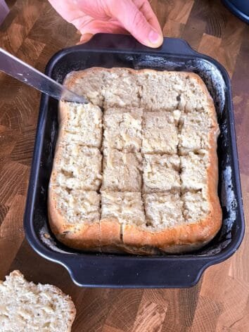 Flatbread cut into square pieces inside a black baking pan.