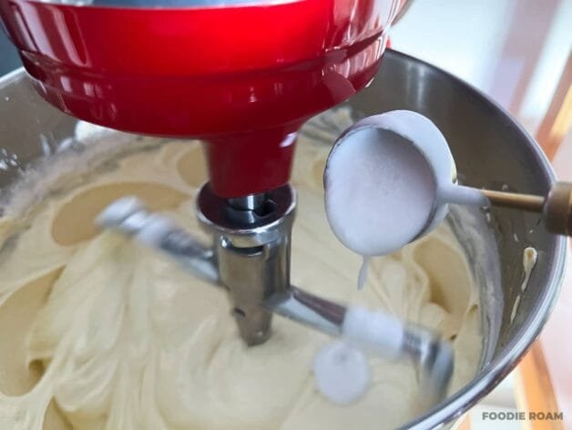 Coconut cream being added to the cake batter in a stand mixer.