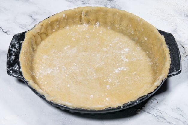 Pie dough placed in a black pie dish, ready to be filled with apple pie filling.