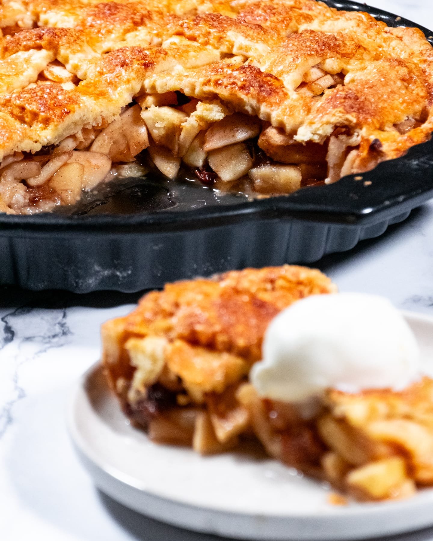A golden-brown apple pie with a flaky crust, partially sliced to reveal juicy tart apples inside.