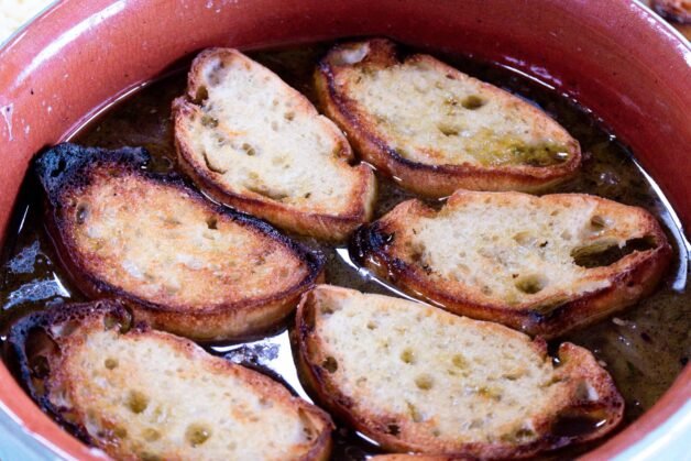 Toasted baguette slices floating on French onion soup.