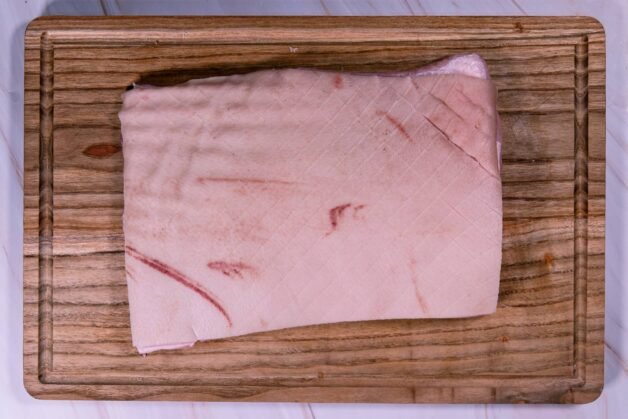 Raw pork belly with a scored diamond pattern on the skin.