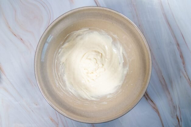 Smooth cream cheese mixture in a mixing bowl, prepared as the base for whipped topping.