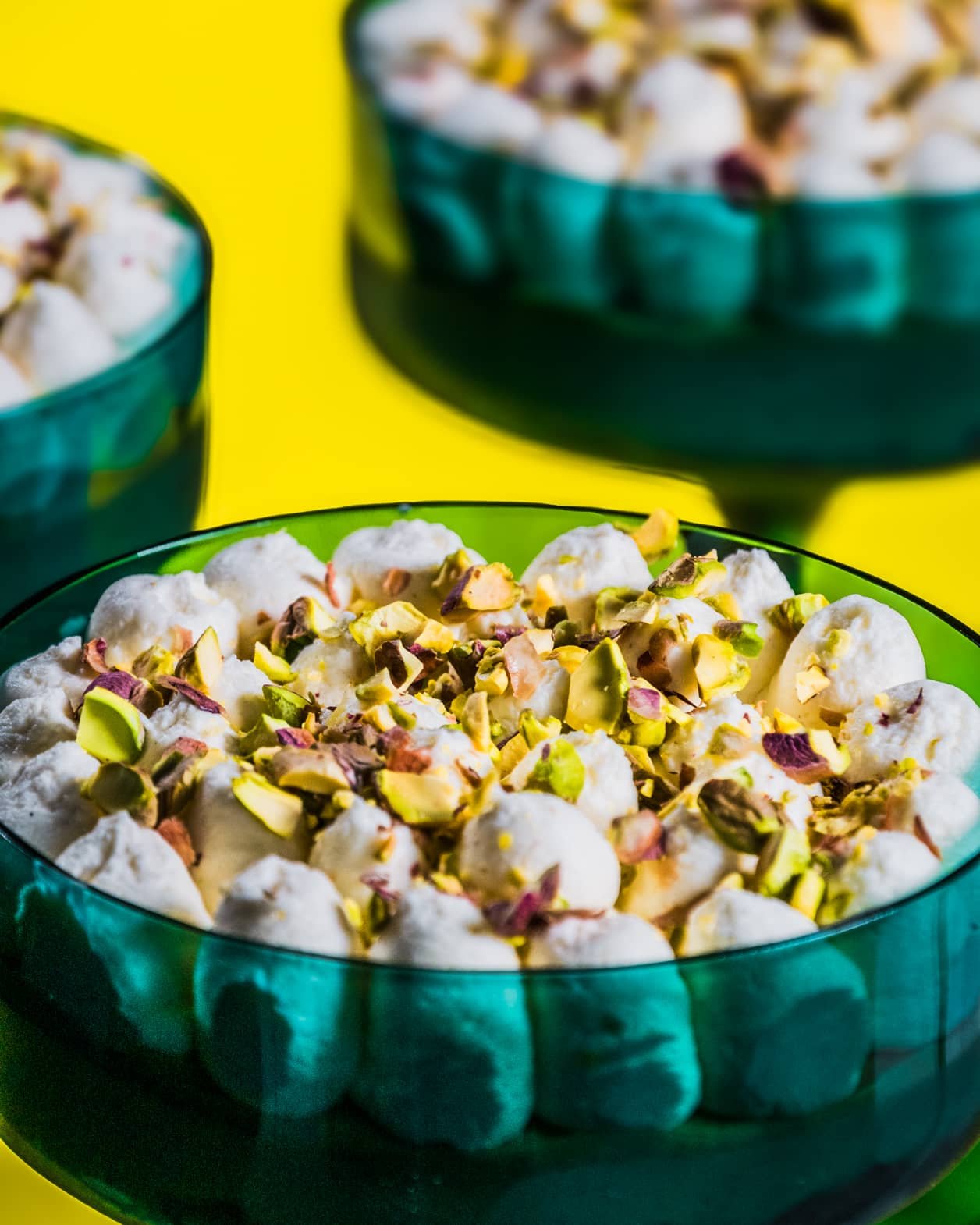 Three dessert cups filled with Pistachio Delight, topped with whipped cream and chopped pistachios.