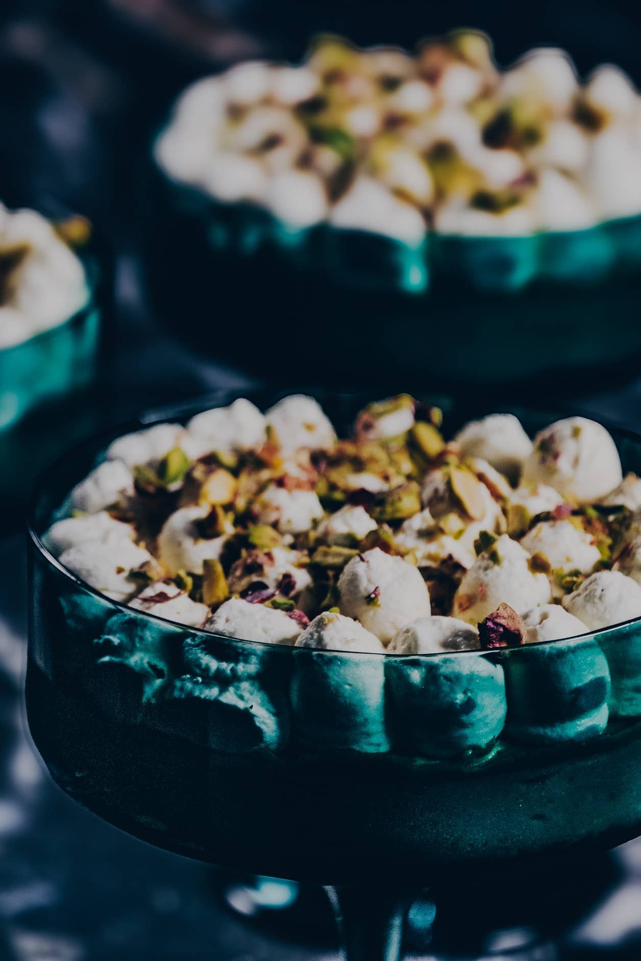 A close-up of Pistachio Delight dessert cups showcasing creamy whipped topping sprinkled with chopped pistachios in elegant green glass cups.