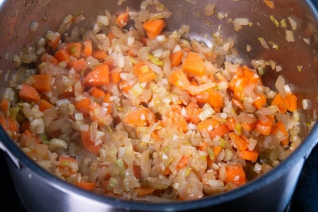 Chopped onions, carrots, and celery sautéing in a pot.