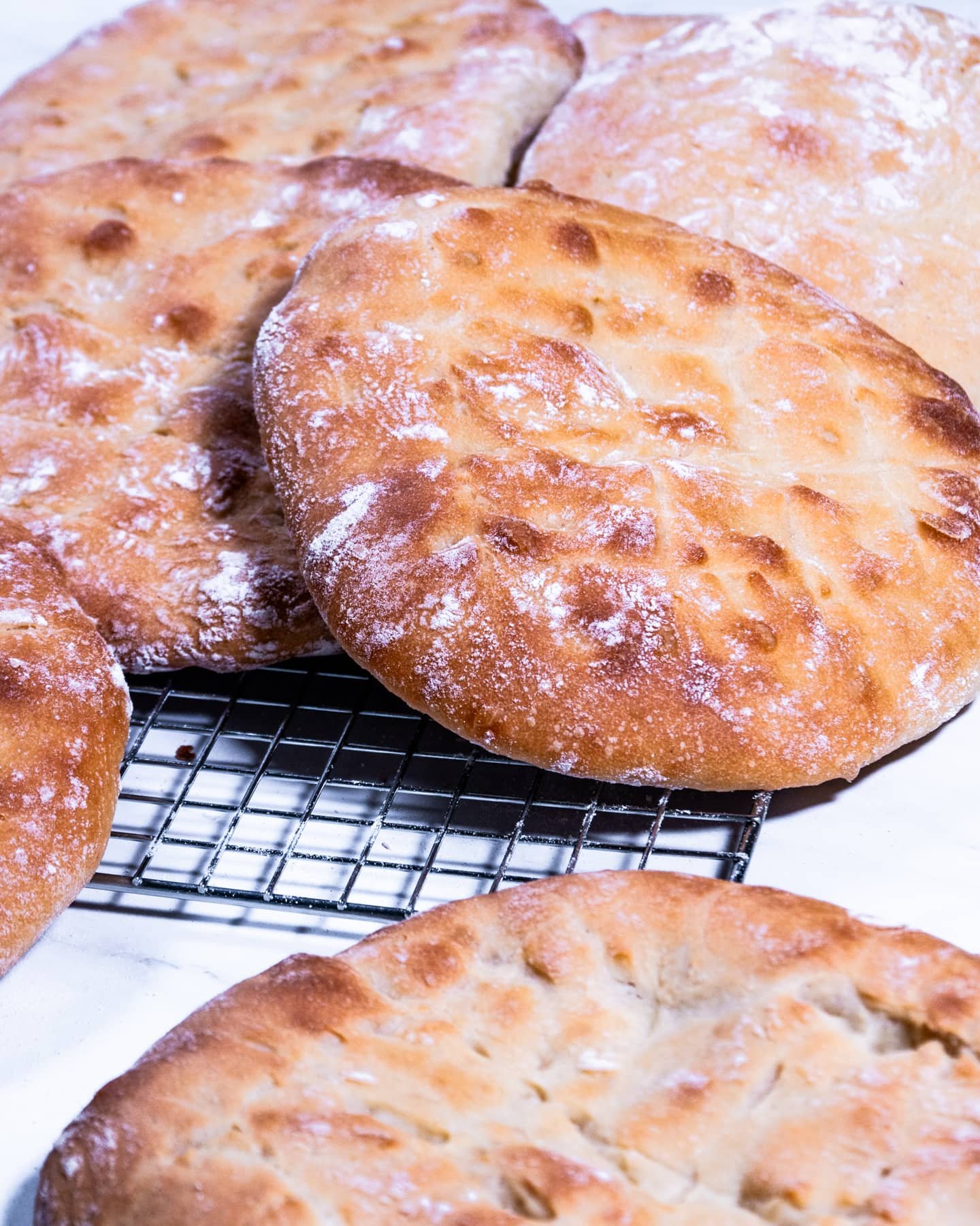 Golden-brown flatbreads cooling on a wire rack after baking.