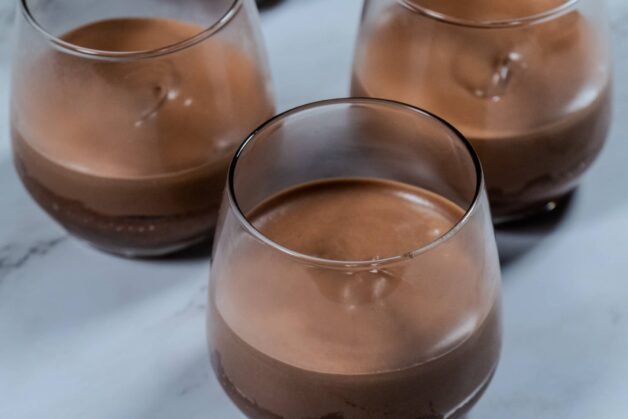 Milk chocolate mousse layer set in glass cups, ready for the final white chocolate layer.