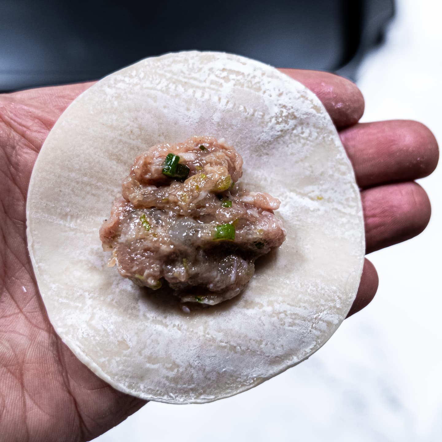 A dumpling wrapper with shrimp and pork filling placed in the center, ready for folding.