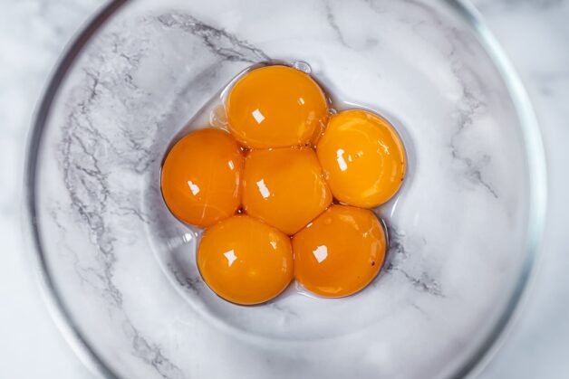 Fresh egg yolks in a glass bowl, the essential ingredient for making the rich and creamy base of an authentic Italian tiramisu.